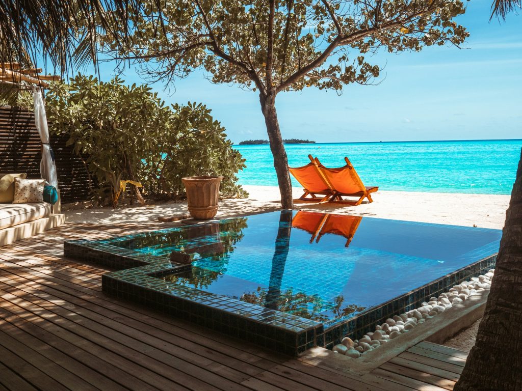 brown-wooden-lounge-chair-beside-swimming-pool